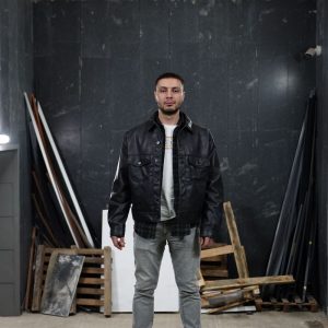 Buneri.es | Cómo Reconocer una Chaqueta de Cuero de Calidad Antes de Comprar Hombre confiado con una chaqueta de cuero negra en un espacio industrial