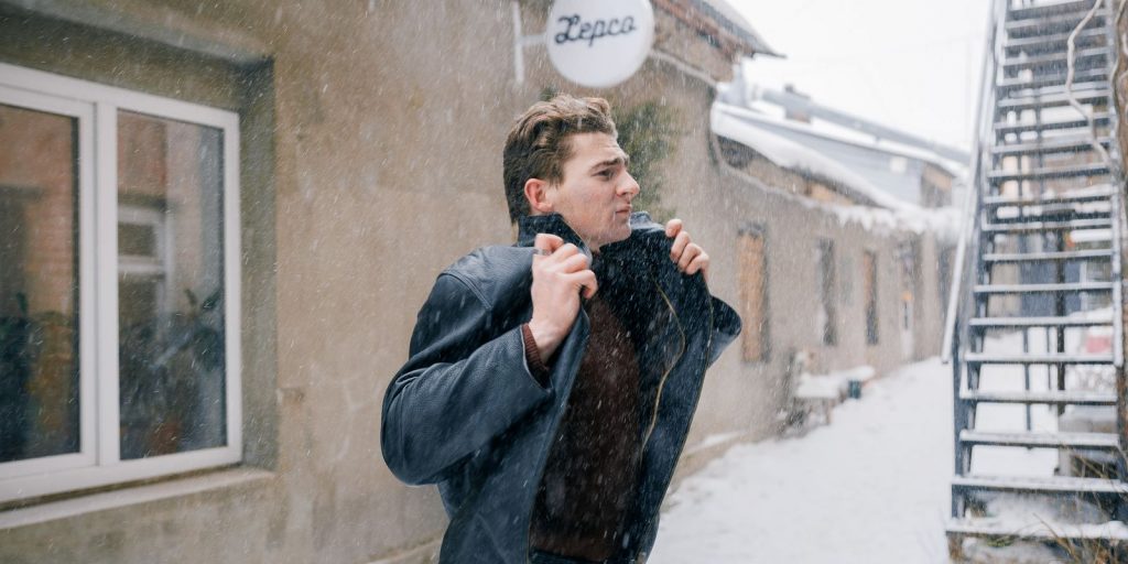 Hombre caminando al aire libre en invierno subiéndose el cuello contra el frío