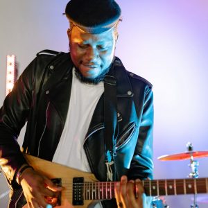 Buneri.es | Por qué los directores tecnológicos y las estrellas del rock viven en chaqueta de cuero Guitarrista tocando una guitarra eléctrica en el escenario con luces vibrantes, vistiendo chaqueta de cuero y gorra plana