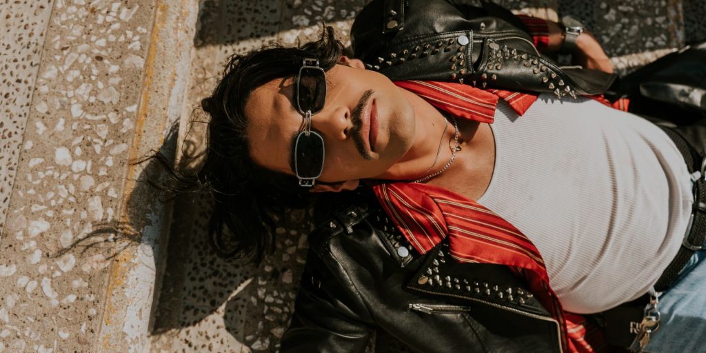 Hombre con chaqueta de cuero relajándose al aire libre sobre unos escalones de piedra