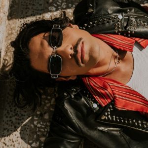 Buneri.es | ¿Qué ponerse debajo de una chaqueta de cuero? (Hombre y mujer) Hombre con chaqueta de cuero relajándose al aire libre sobre unos escalones de piedra