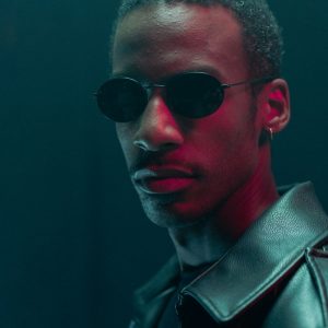 Buneri.es | ¿Vale la pena una chaqueta de cuero auténtico? Retrato estilizado de un hombre con gafas de sol y chaqueta de cuero en un ambiente dramático